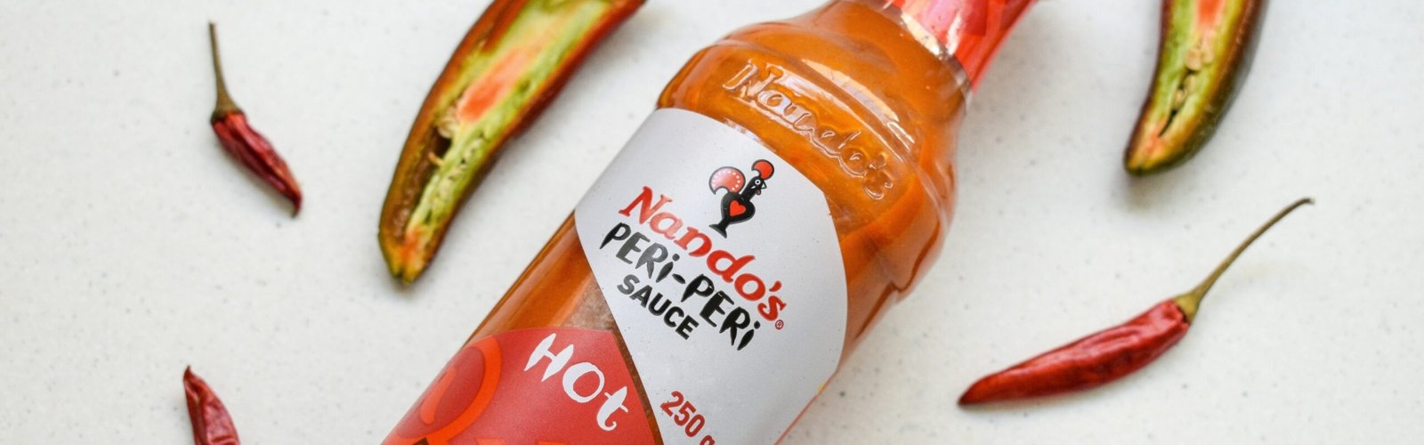 a bottle of hot sauce surrounded by hot peppers