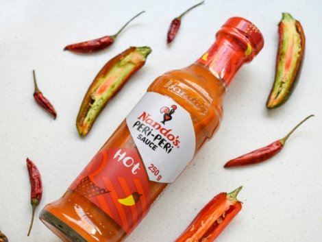 a bottle of hot sauce surrounded by hot peppers